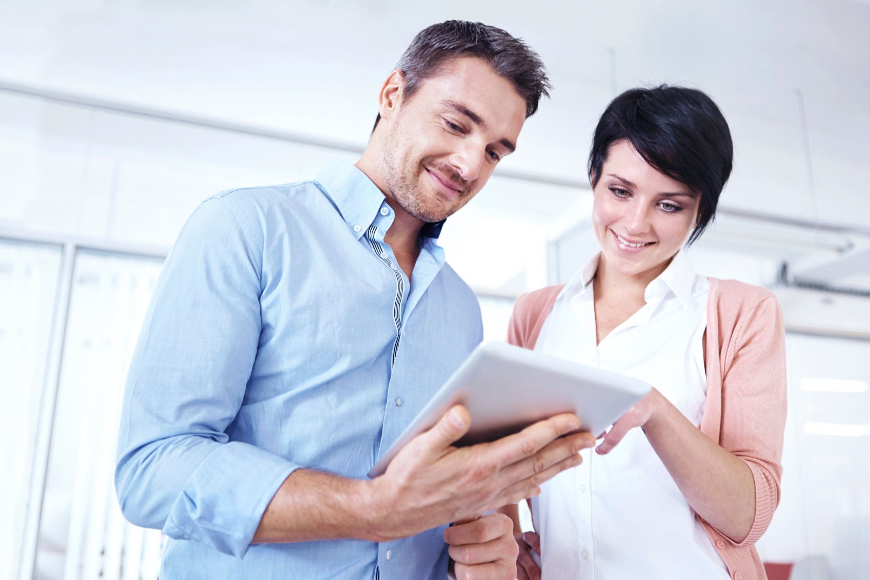 Two businesspeople standing together in the office and looking at a digital tablet